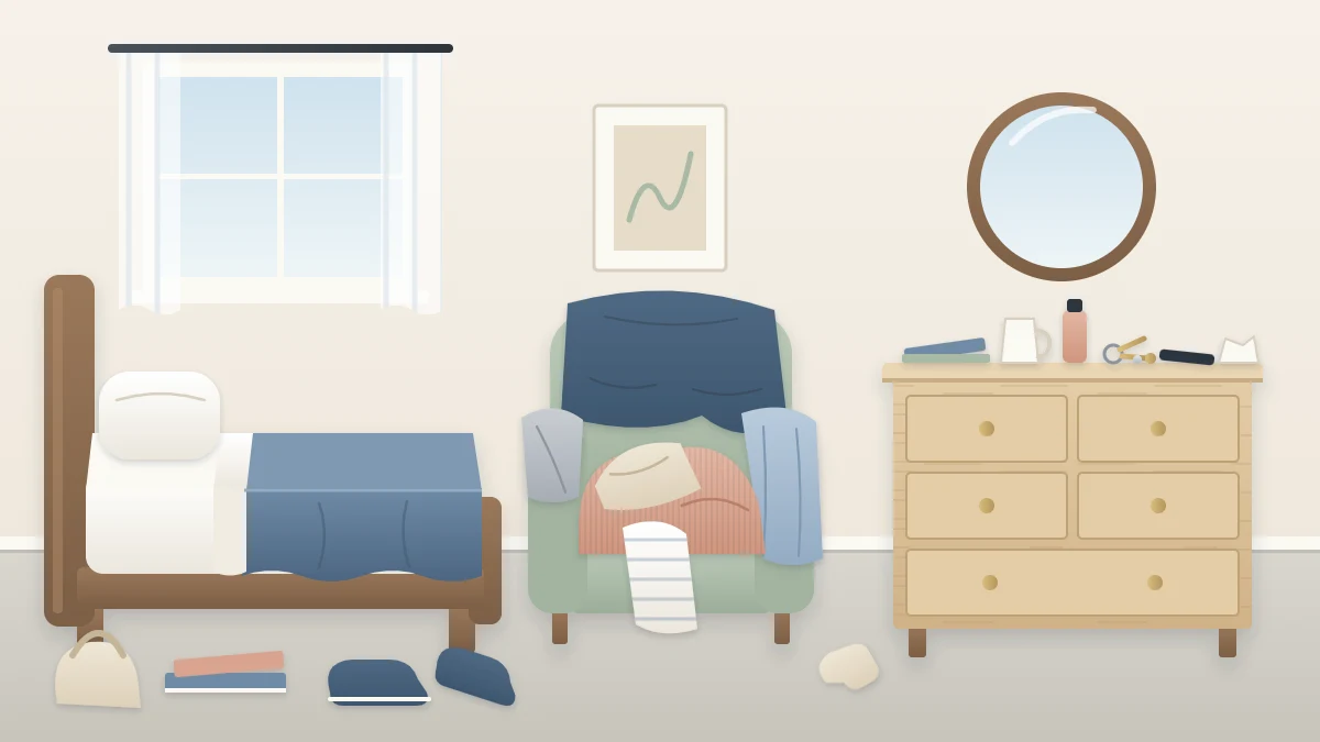 A bedroom corner with an armchair piled with worn clothes, a dresser top scattered with small objects and a few items on the floor by the bed