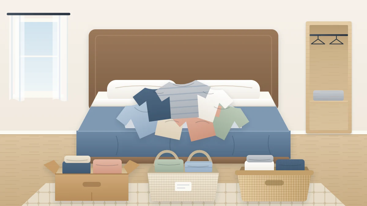 A bed used as a sorting surface with a loose pile of T-shirts on it and three open bags or boxes of folded clothes on the floor