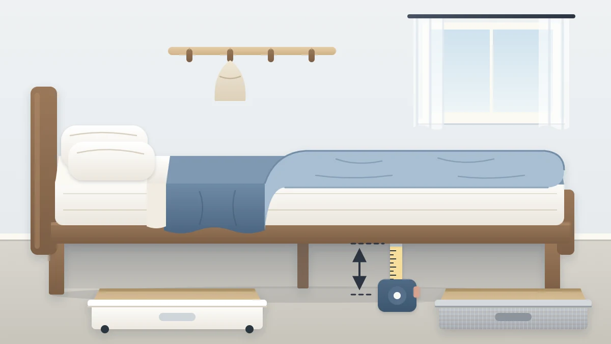 A bed with the duvet lifted and a tape measure standing between the floor and the side rail, two empty shallow boxes waiting beside it
